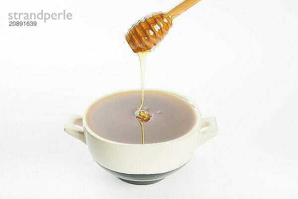 Juicy honey in a cup and spoon on white background