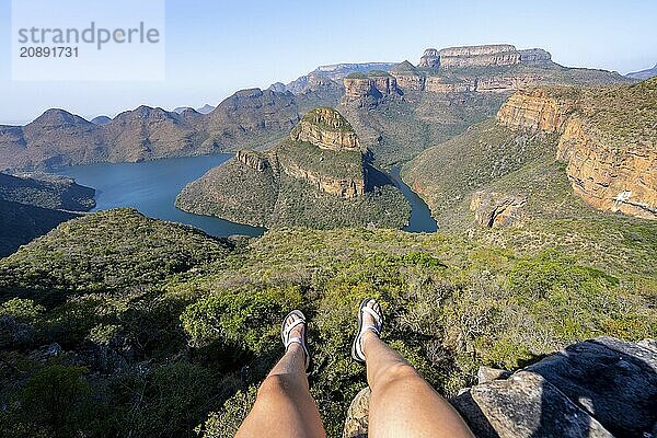 Legs of a sitting woman  view of river bend at Blyde River Canyon with Three Rondawels peak  view of canyon with Blyde River and table mountains in the evening light  canyon landscape  Panorama Route  Mpumalanga  South Africa  Africa