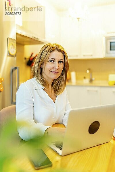 Vertical portrait of a casual blonde businesswoman looking at camera working from home