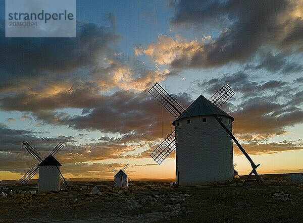 Three windmills in front of a dramatic sunset with a colourful sky and clouds. The silhouettes of the windmills stand out against the atmospheric light. Aerial view  windmills  Campo de Criptana  province of Ciudad Real  Castilla-La Mancha  Route of Don Quixote  Spain  Europe