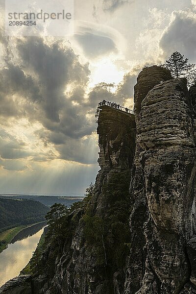 The Bastei is a rock formation with a viewing platform in Saxon Switzerland on the right bank of the River Elbe in the municipality of Lohmen between the spa town of Rathen and the town of Wehlen. It is one of the most visited tourist attractions in Saxon Switzerland. Dramatic sky over the Bastei. ourists on the new viewing platform  Saxon Switzerland  Rathen  Saxony  Germany  Europe