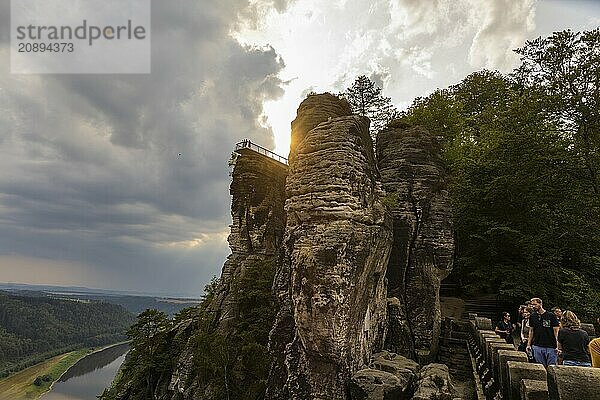 The Bastei is a rock formation with a viewing platform in Saxon Switzerland on the right bank of the River Elbe in the municipality of Lohmen between the spa town of Rathen and the town of Wehlen. It is one of the most visited tourist attractions in Saxon Switzerland. Dramatic sky over the Bastei. ourists on the new viewing platform  Saxon Switzerland  Rathen  Saxony  Germany  Europe