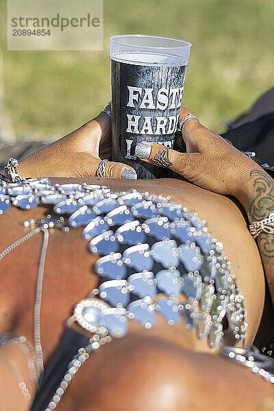 A festival visitor from Norway relaxes lying down with a Wacken cup in her hand at the Wacken Open Air in Wacken. The traditional metal festival takes place from 31 July to 2 August 2024