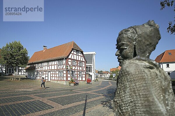 Museum of local history and blurred sculpture Sitting Soraya by Karlheinz Oswald 2017  half-timbered house  bronze  sitting  woman  Eschenplatz  Eschborn  Hesse  Germany  Europe