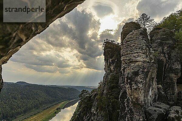 The Bastei is a rock formation with a viewing platform in Saxon Switzerland on the right bank of the River Elbe in the municipality of Lohmen between the spa town of Rathen and the town of Wehlen. It is one of the most visited tourist attractions in Saxon Switzerland. Dramatic sky over the Bastei. ourists on the new viewing platform  Saxon Switzerland  Rathen  Saxony  Germany  Europe