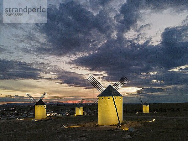 Several illuminated windmills in a rural landscape at sunset  aerial view  windmills  Campo de Criptana  Ciudad Real province  Castilla-La Mancha  Route of Don Quixote  Spain  Europe