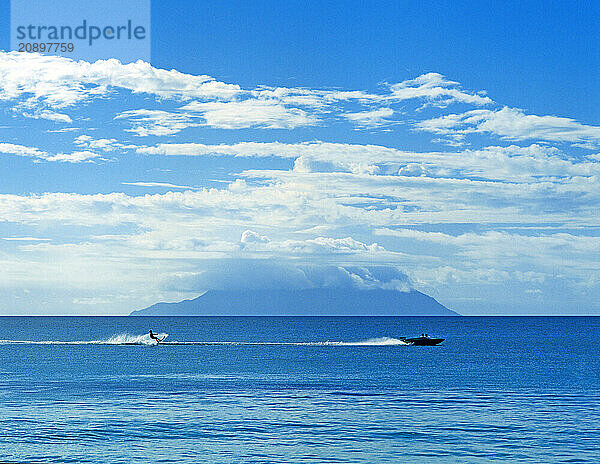 Seychelles. Water skier with Silhouette Island viewed from Mahé.