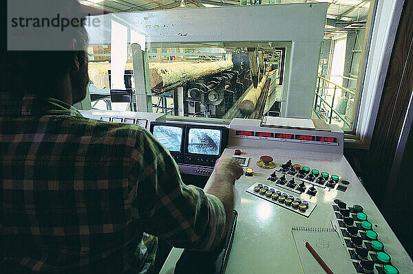 Australia. Queensland. Sawmill. Man in computerised control room.