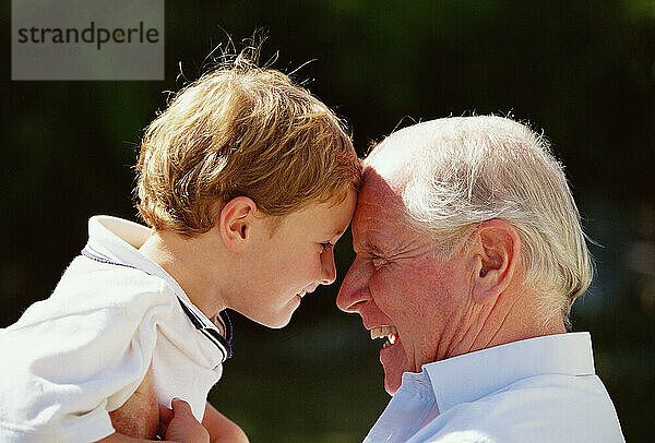 Grandfather and grandson. Close up profile outdoors in garden.