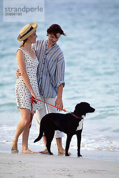 Young couple with their dog walking on the beach.