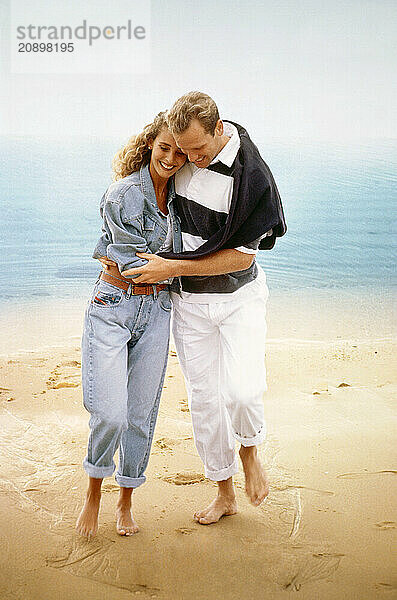 Young couple walking barefoot on the beach.