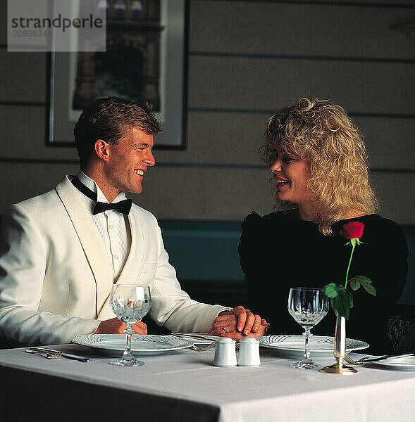 Couple in evening dress sitting at restaurant table.