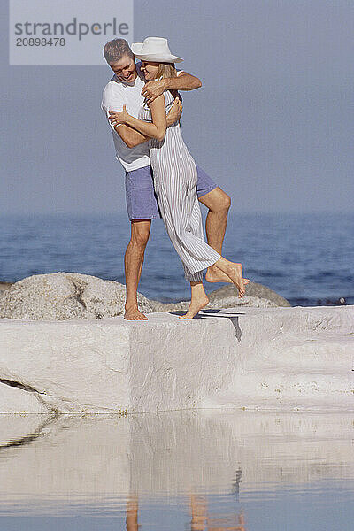 Young couple standing outdoors by saltwater pool.