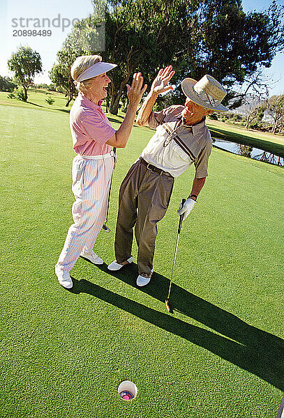 Retirement age couple on golf course putting green.