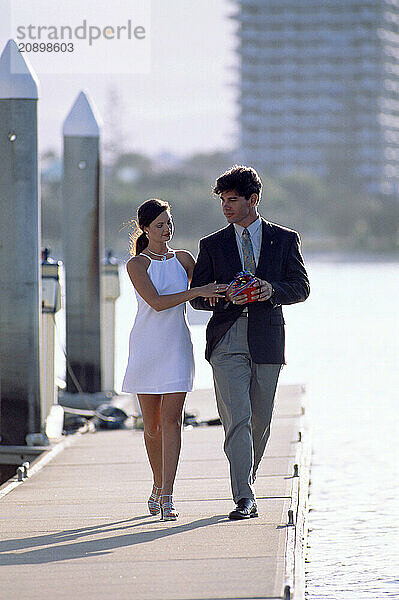 Australia. Queensland. Gold Coast. Young couple on marina pontoon.