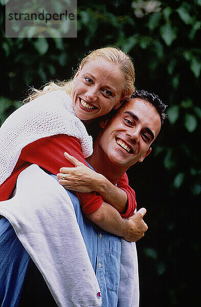 Outdoor portrait of young couple in garden.