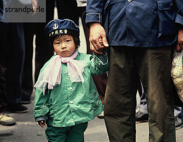 China. Shanghai. Crowded street close up of little girl holding father's hand.