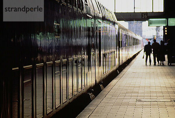 Germany. Railway station with passenger train & people on platform.