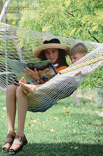 Children. Boy & girl outdoors in hammock.