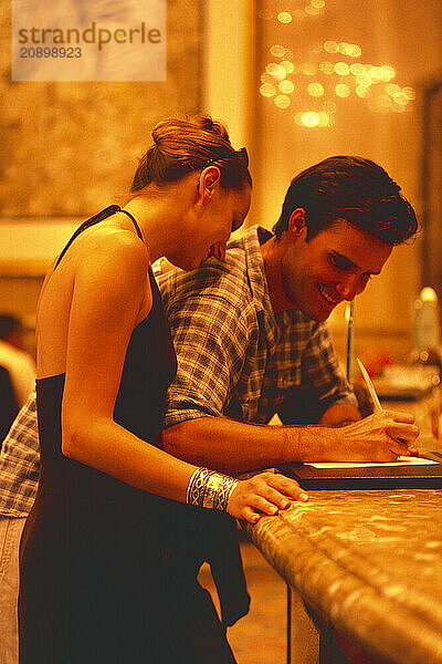 Singapore. Tourist young couple signing-in at hotel reception.