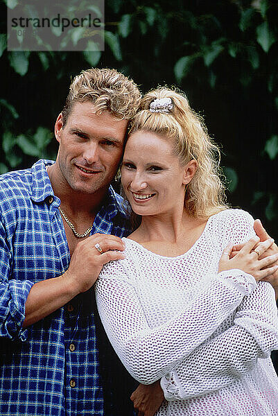 Outdoor portrait of young couple in garden.