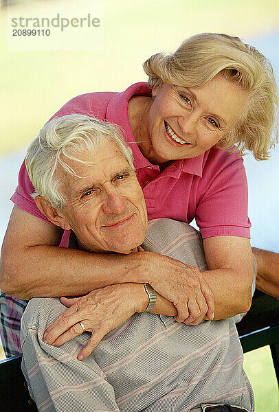 Portrait of senior man & woman couple sitting outdoors.