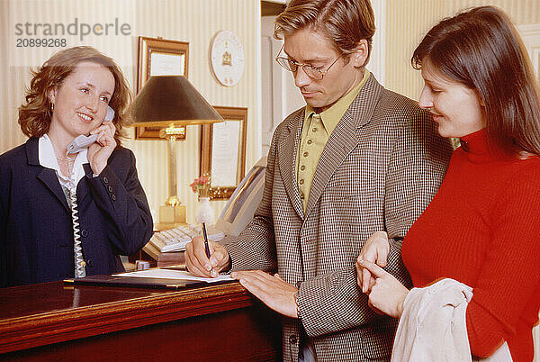 Young couple checking in at hotel reception desk.