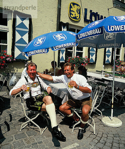 Germany. Munich. Two men drinking beer on outdoor bar terrace.