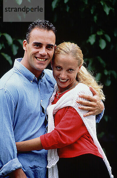 Outdoor portrait of young couple in garden.