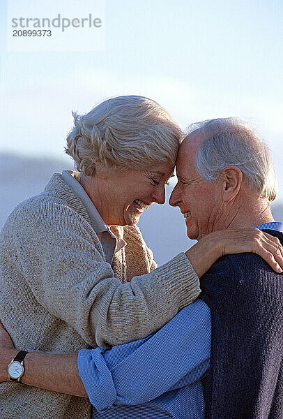 Senior man & woman couple outdoors close up in affectionate embrace.