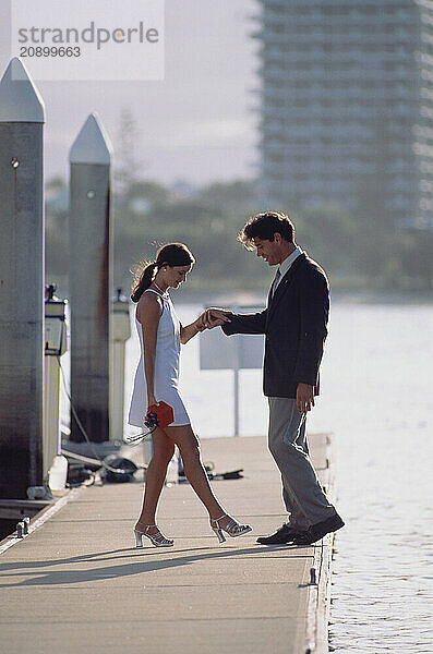 Australia. Queensland. Gold Coast. Young couple on marina pontoon.