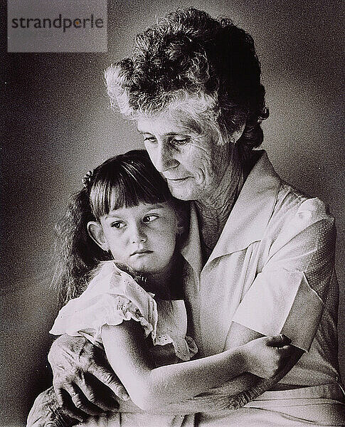 Grandmother and granddaughter sitting indoors.