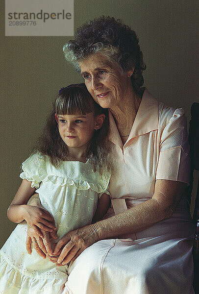 Grandmother and granddaughter sitting indoors.