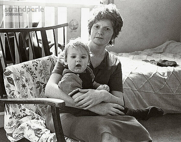 Mother & child sitting together in bed sitting room.