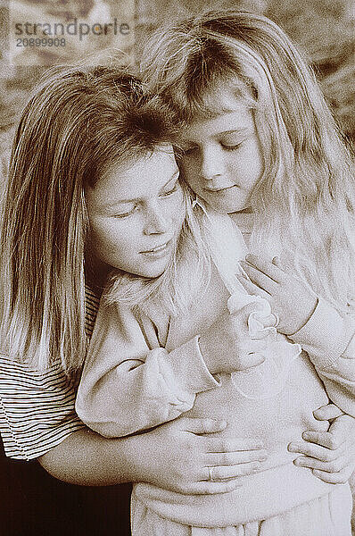 Outdoor close up of mother hugging young daughter.