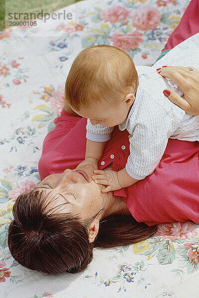 Family. Mother & baby lying on blanket in the garden.