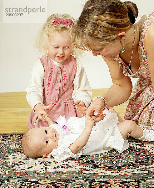 Mother with daughter playing with new baby.