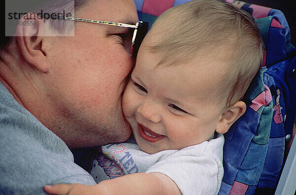 Family. Close up of father embracing smiling baby.