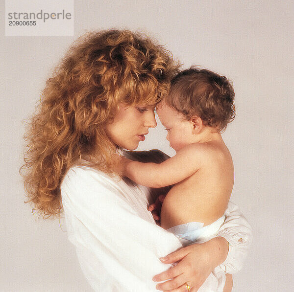 Young woman & baby. Mother & son studio portrait in profile.