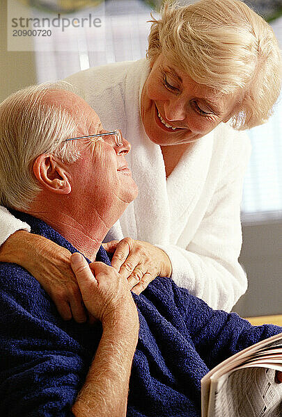 Senior man & woman couple in bathrobes indoors at home.