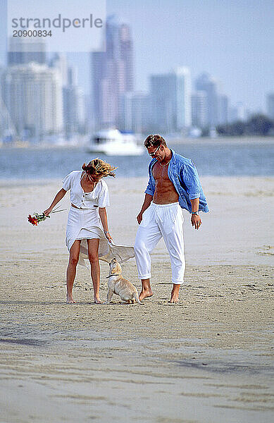 Australia. Queensland. Gold Coast. Young couple with their dog on the beach.