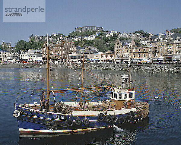 Scotland. Oban. View of town harbour waterfront with fishing boat.