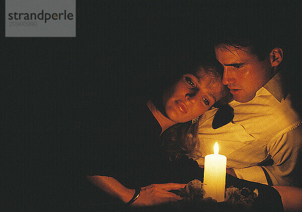 Close up of young  romantic couple indoors by candlelight.