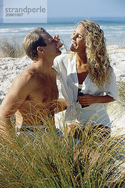 Young couple applying sunscreen at the beach.