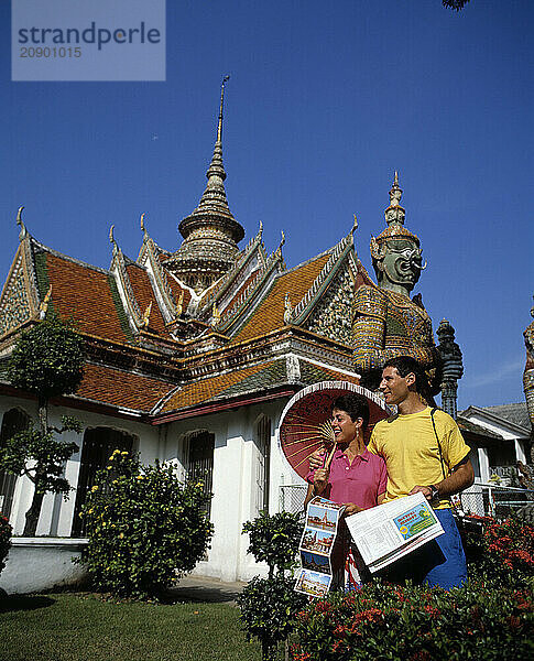 Thailand. Bangkok. Tourist couple in front of Wat Arun Temple of Dawn.