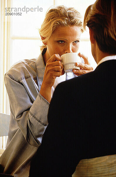 Young couple sitting indoors drinking coffee.