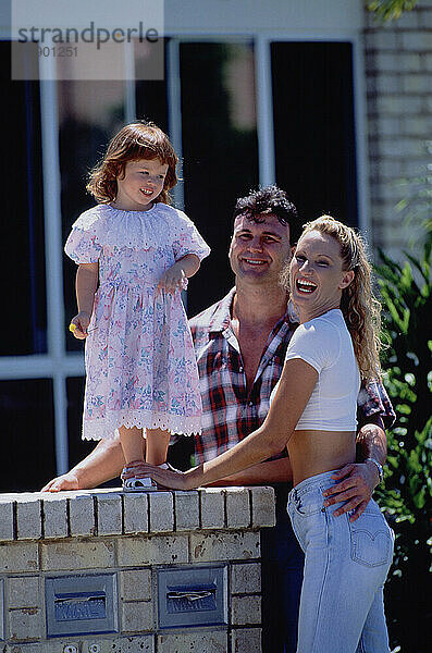 Family. Parents with little daughter outside building.