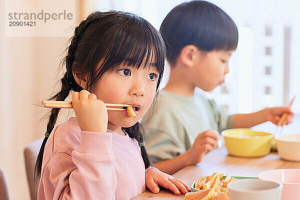 Happy Japanese kids eating in the dining room