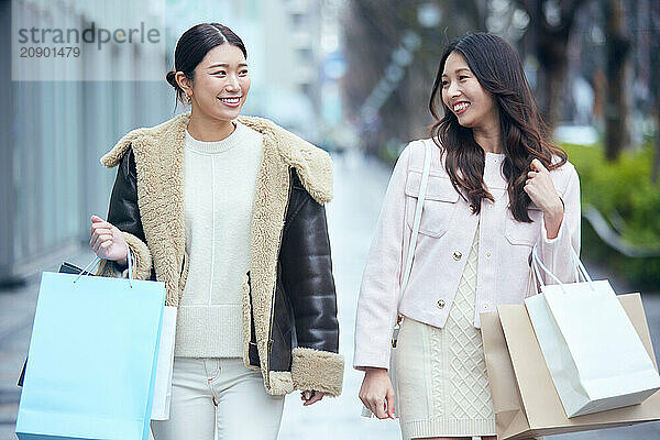 Two Asian Women Walking Down The Street With Shopping Bags