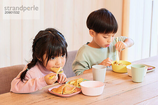 Happy Japanese kids eating in the dining room